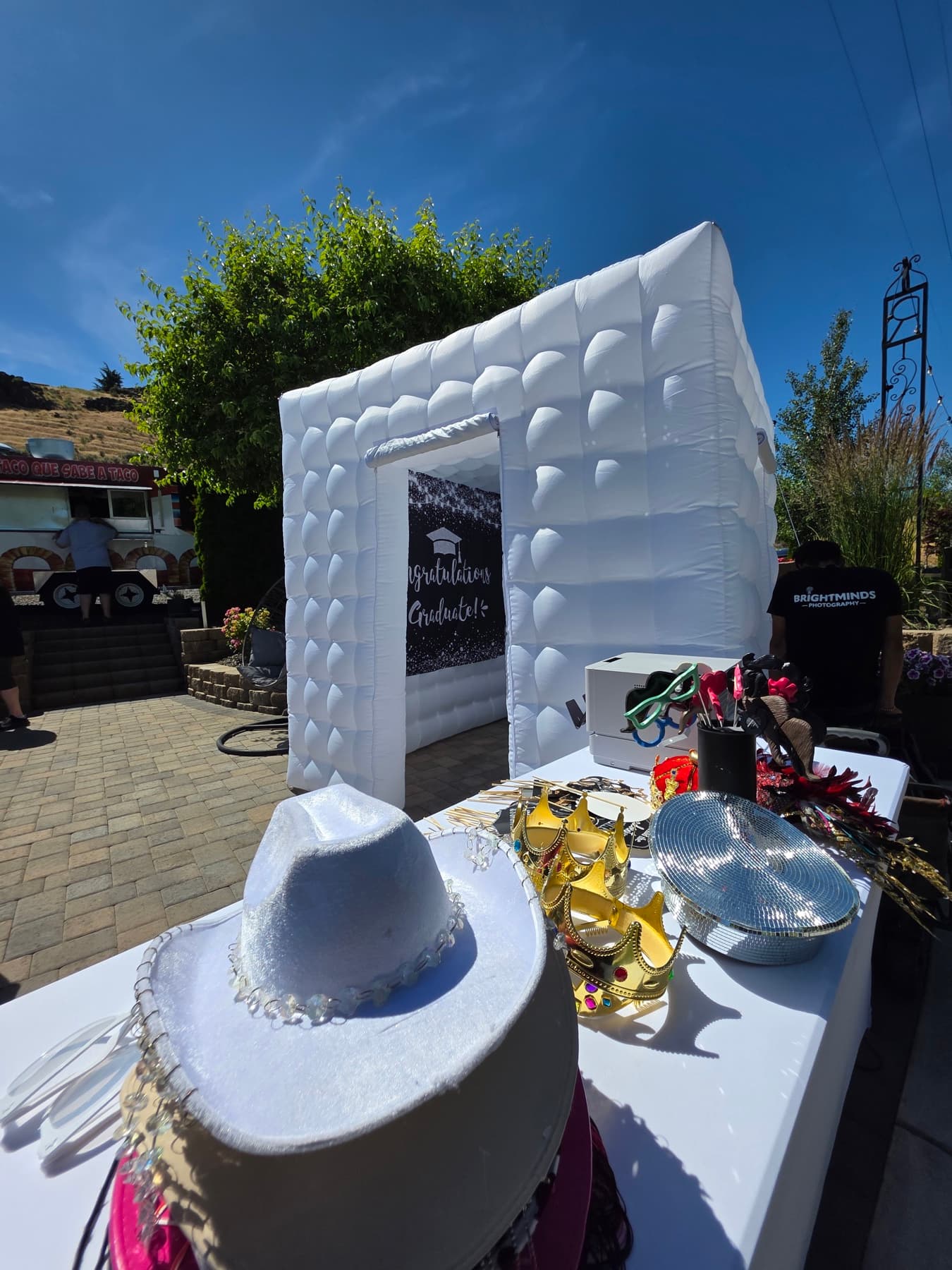 Outdoor photo booth setup with hats, crowns, glasses, and a custom backdrop